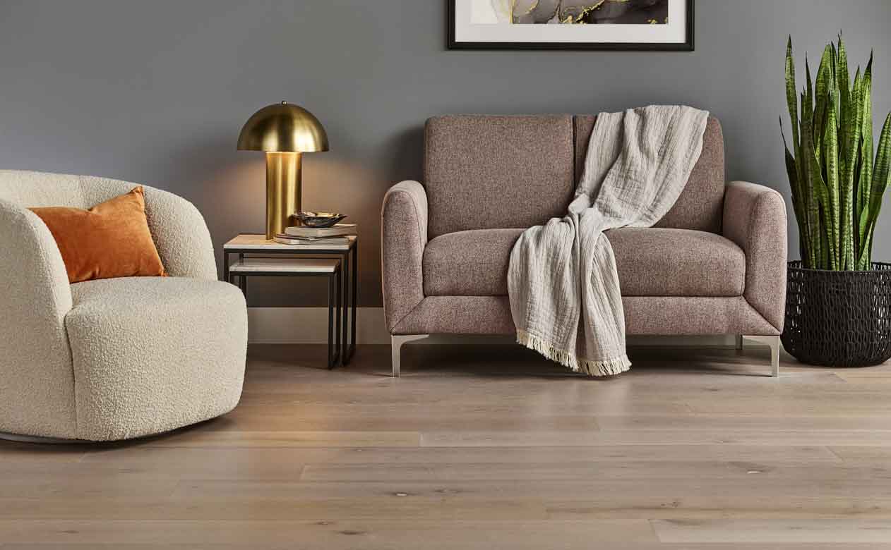 brown hardwood floors in a living room with brown loveseat and cream accent chair